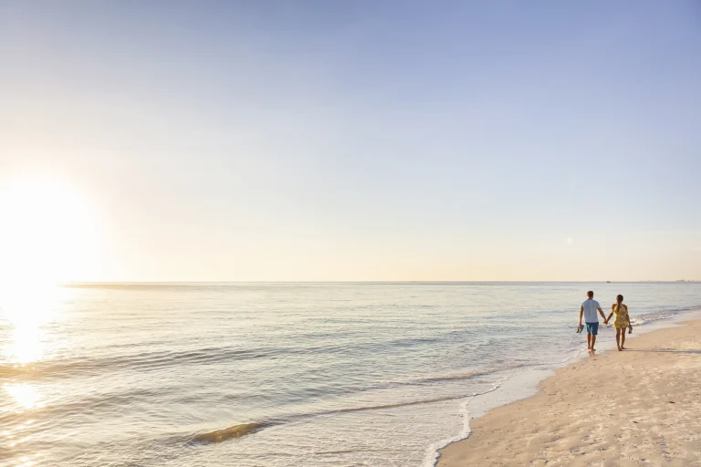 A couple walking on a beach at sunset